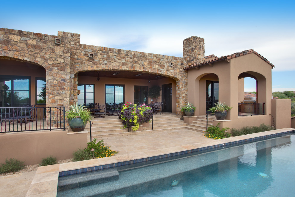Design ideas for an expansive backyard patio in Phoenix with natural stone pavers, a roof extension and an outdoor kitchen.