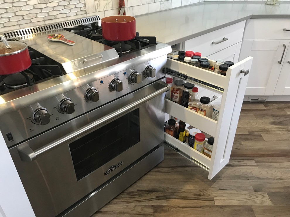 Eat-in kitchen - large transitional single-wall light wood floor and gray floor eat-in kitchen idea in Atlanta with a farmhouse sink, shaker cabinets, white cabinets, quartzite countertops, white backsplash, marble backsplash, stainless steel appliances, an island and white countertops