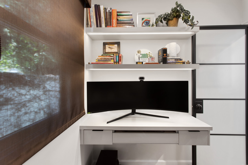 Cette image montre un petit bureau design avec un mur gris, un sol en bois brun et un bureau intégré.