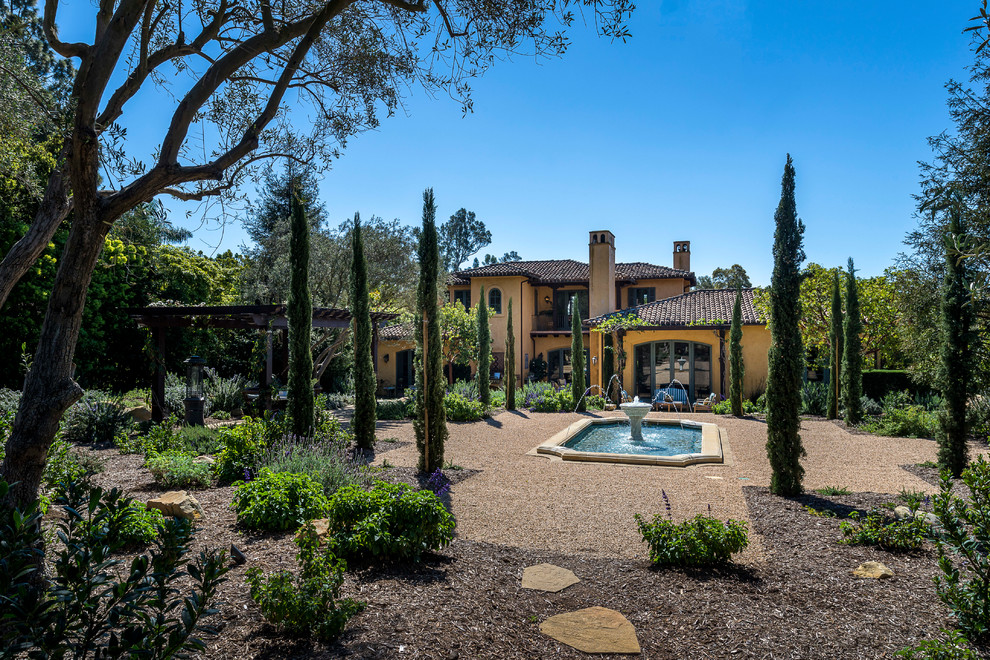 This is an example of a large mediterranean backyard full sun formal garden for spring in Santa Barbara with a water feature and gravel.