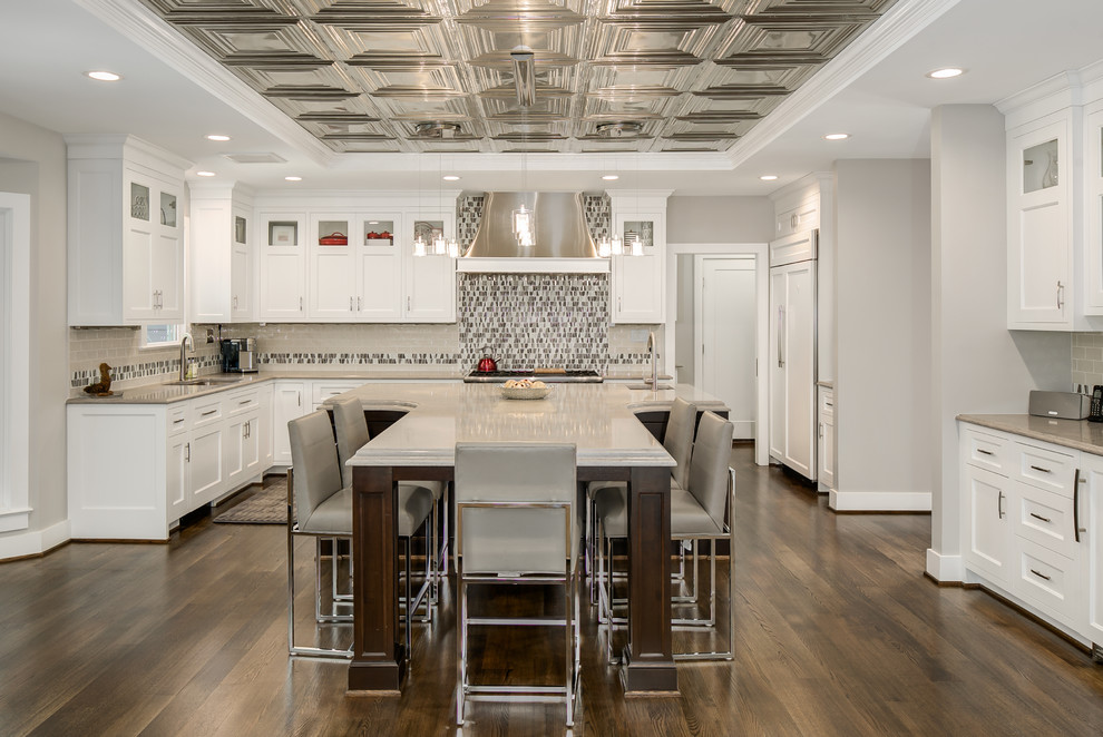 Inspiration for a mid-sized transitional u-shaped dark wood floor and brown floor eat-in kitchen remodel in DC Metro with an undermount sink, shaker cabinets, white cabinets, solid surface countertops, beige backsplash, porcelain backsplash, stainless steel appliances and an island