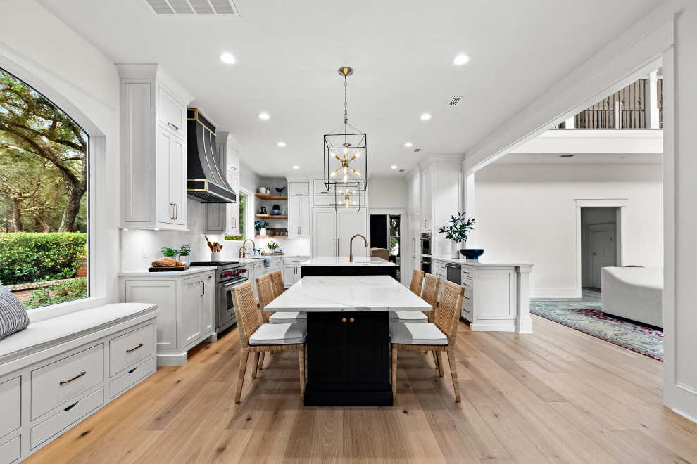 Kitchen - large transitional u-shaped light wood floor kitchen idea with an undermount sink, shaker cabinets, white cabinets, quartz countertops, white backsplash, marble backsplash, paneled appliances, two islands and white countertops
