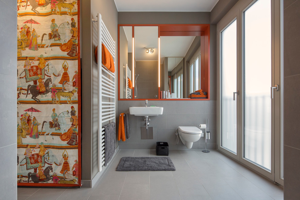 Design ideas for a mid-sized contemporary bathroom in Berlin with a wall-mount toilet, gray tile, a wall-mount sink, grey walls, open cabinets and orange cabinets.
