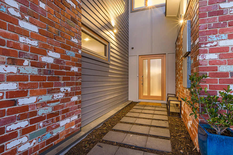 Photo of a small contemporary front door in Canberra - Queanbeyan with grey walls, concrete floors, a single front door and a light wood front door.