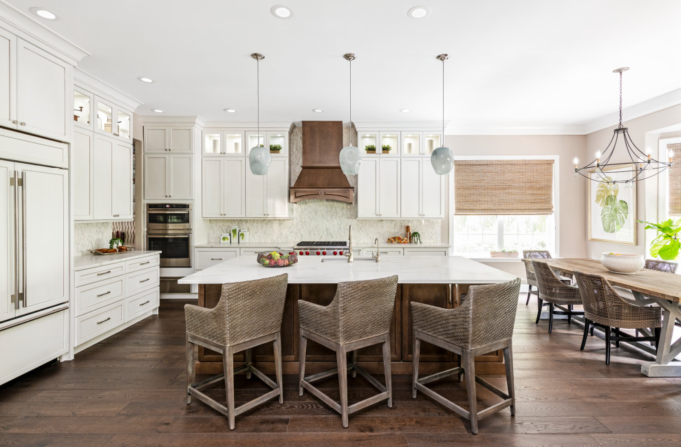 Large transitional l-shaped open plan kitchen in Tampa with an undermount sink, shaker cabinets, white cabinets, quartzite benchtops, white splashback, marble splashback, stainless steel appliances, dark hardwood floors, with island, brown floor and white benchtop.