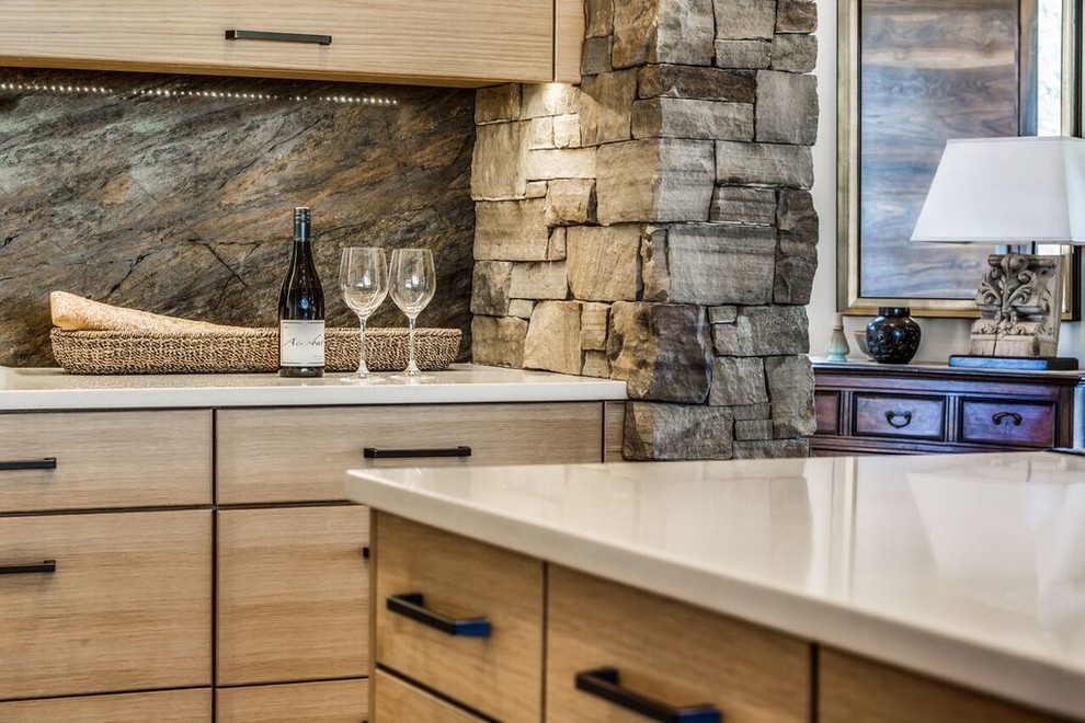 Mid-sized mountain style u-shaped travertine floor open concept kitchen photo with an undermount sink, flat-panel cabinets, light wood cabinets, solid surface countertops, brown backsplash, stone slab backsplash, colored appliances and an island