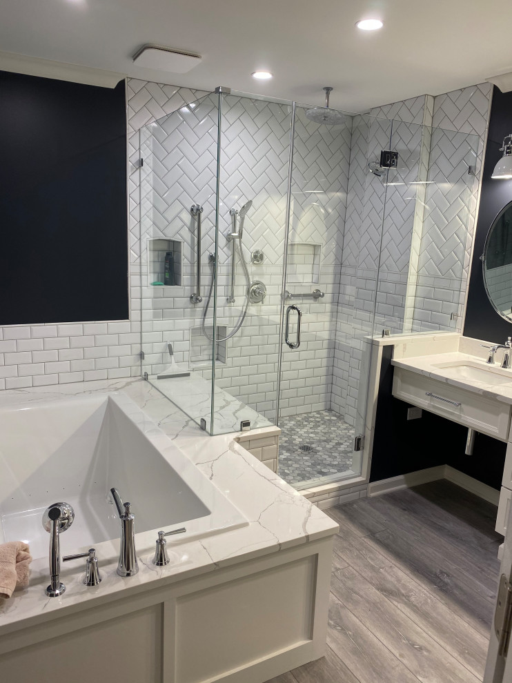 This is an example of a mid-sized contemporary master bathroom in Chicago with recessed-panel cabinets, white cabinets, a hot tub, a double shower, a two-piece toilet, white tile, travertine, black walls, vinyl floors, an undermount sink, marble benchtops, grey floor, a hinged shower door, white benchtops, a niche, a double vanity and a built-in vanity.