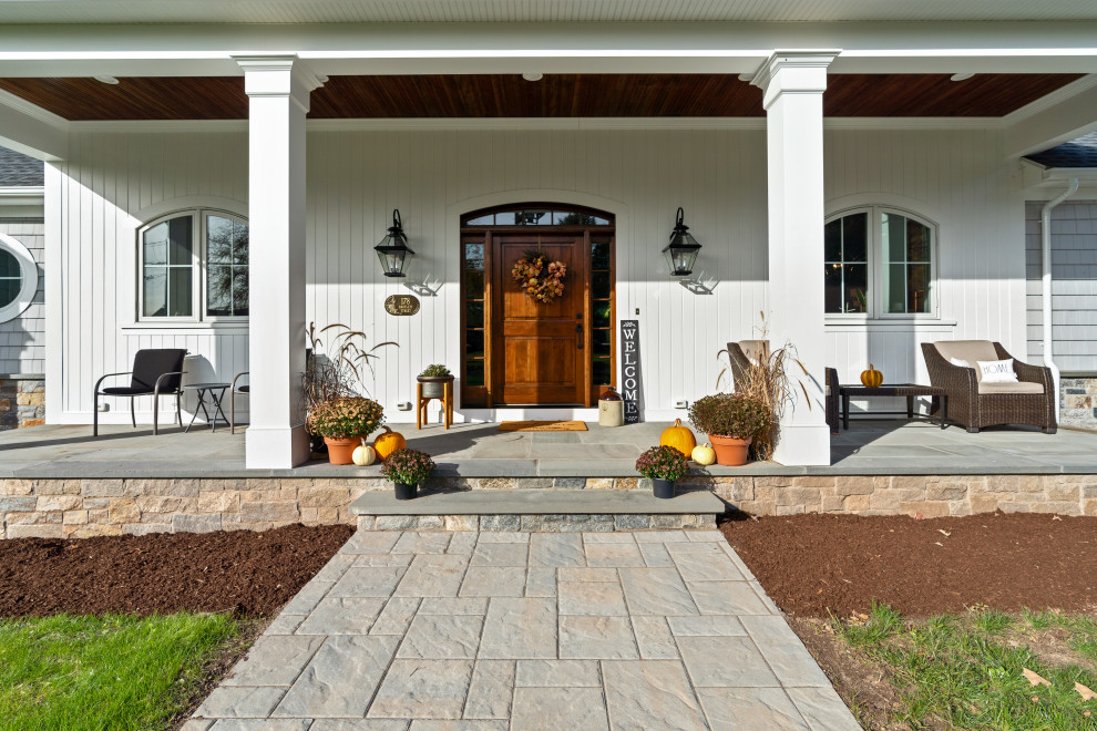Cette image montre un grand porche d'entrée de maison avant rustique avec des colonnes et une extension de toiture.
