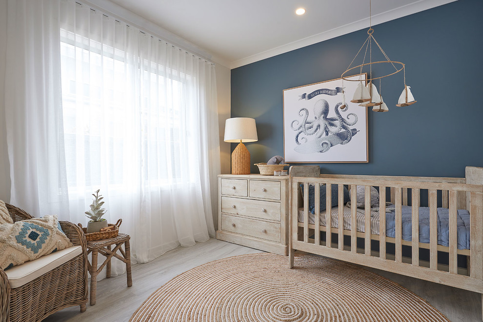 This is an example of a beach style nursery for boys in Melbourne with white walls, light hardwood floors and beige floor.