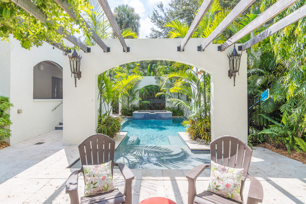 This is an example of a tropical backyard custom-shaped pool in Orlando with a water feature.