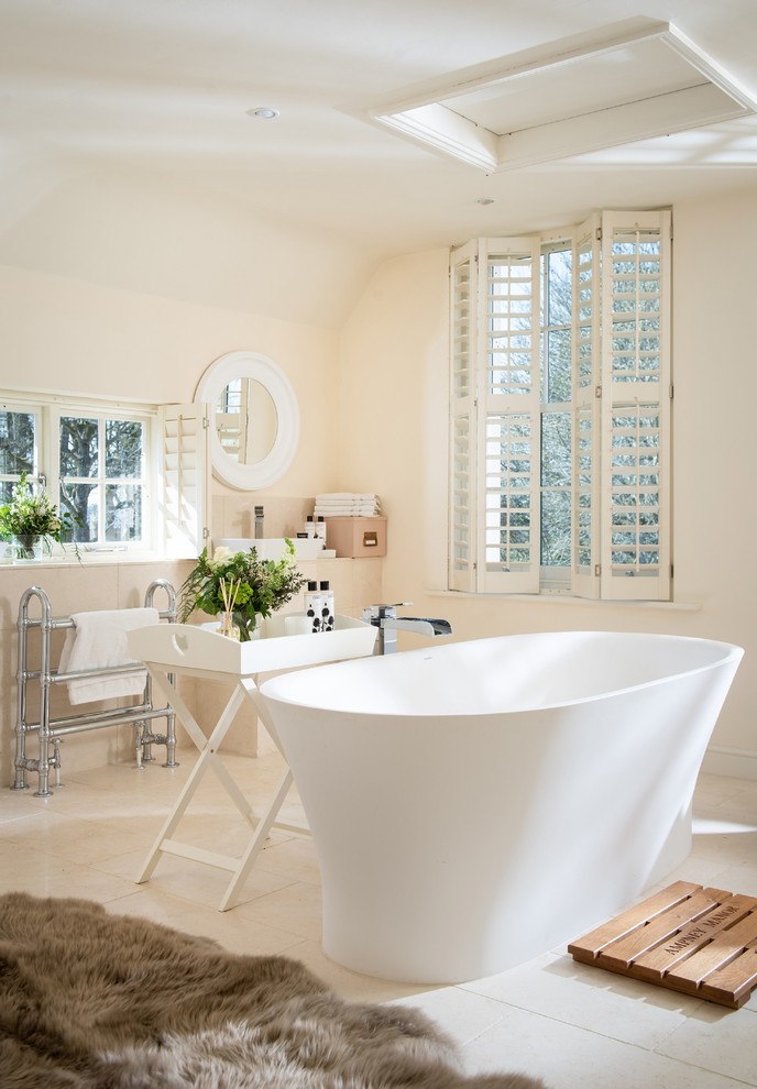 Example of a mid-sized transitional limestone floor and beige floor freestanding bathtub design in Cornwall with beige walls, beige countertops and a vessel sink
