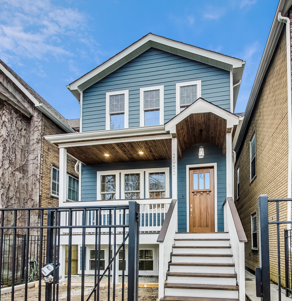 This is an example of a large traditional two-storey blue house exterior in Chicago with concrete fiberboard siding, a gable roof, a shingle roof, a brown roof and clapboard siding.