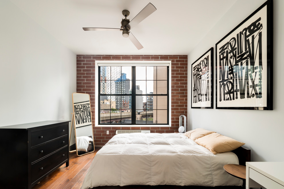 Inspiration for a small industrial bedroom in New York with white walls, medium hardwood floors and no fireplace.