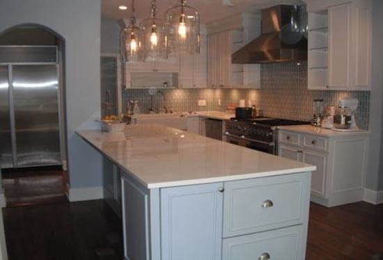 Kitchen pantry - l-shaped medium tone wood floor kitchen pantry idea in Miami with beaded inset cabinets, white cabinets, solid surface countertops, matchstick tile backsplash, stainless steel appliances, an island and gray backsplash