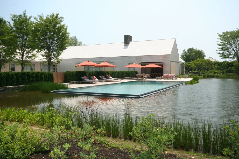 Inspiration for a contemporary backyard rectangular infinity pool in New York with decking.