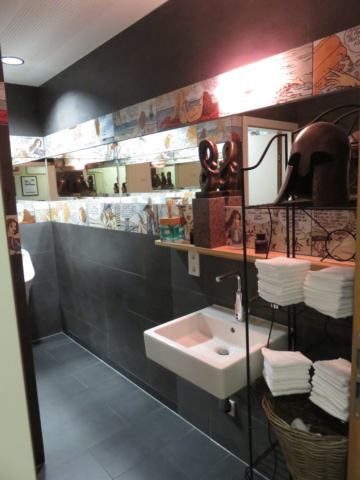 На фото: туалет среднего размера в стиле фьюжн с инсталляцией, черной плиткой, керамической плиткой, черными стенами, полом из керамической плитки, подвесной раковиной, стеклянной столешницей, черным полом, подвесной тумбой и многоуровневым потолком с