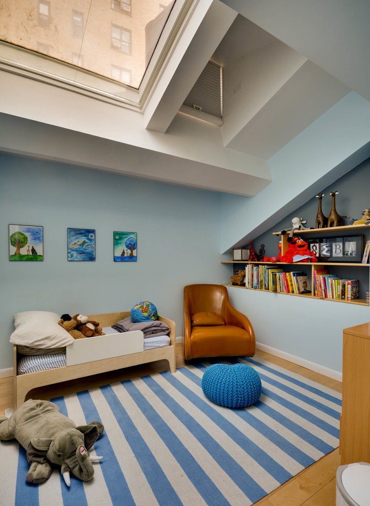 Mid-sized modern kids' room in New York with blue walls, light hardwood floors and beige floor for boys.
