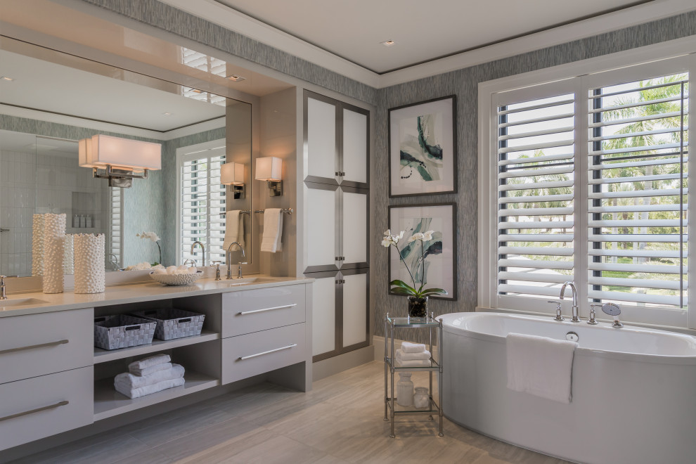 Contemporary bathroom in Miami with flat-panel cabinets, grey cabinets, a freestanding tub, grey walls, an undermount sink, grey floor, beige benchtops, a double vanity, a built-in vanity and wallpaper.