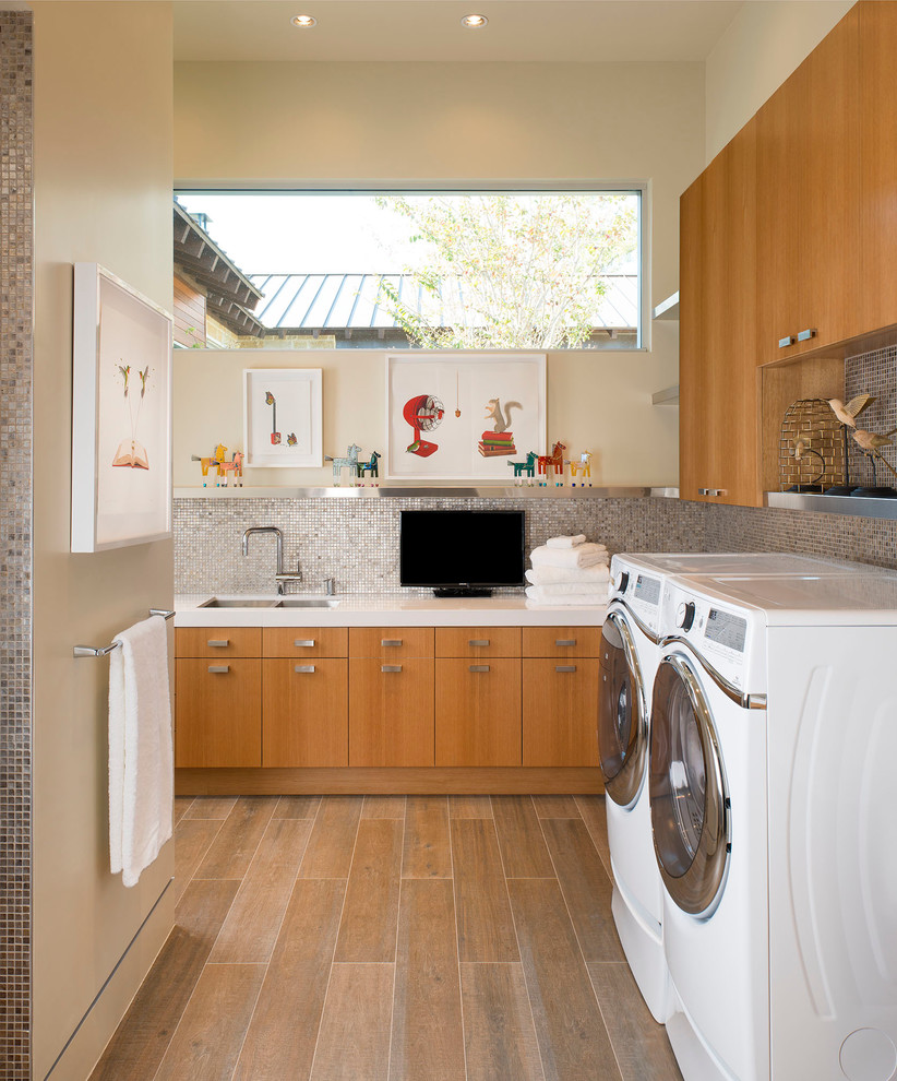 Inspiration for a large midcentury l-shaped dedicated laundry room in Austin with an undermount sink, flat-panel cabinets, medium wood cabinets, quartzite benchtops, beige walls, porcelain floors and a side-by-side washer and dryer.