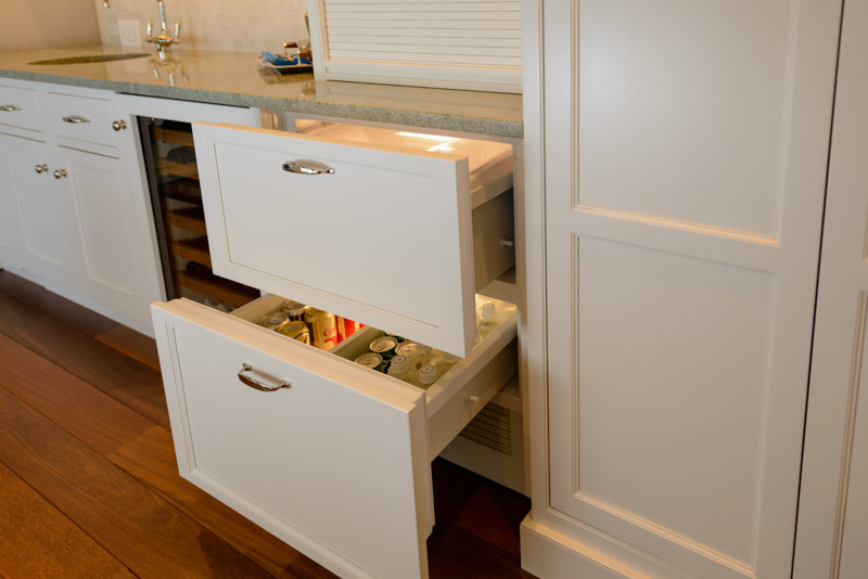 Example of a transitional medium tone wood floor kitchen design in Boston with a triple-bowl sink, recessed-panel cabinets, white cabinets, granite countertops, white backsplash, mosaic tile backsplash, stainless steel appliances and an island