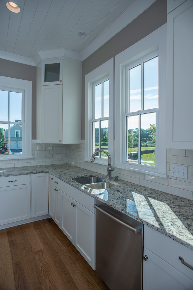 Transitional l-shaped eat-in kitchen in Charleston with an undermount sink, recessed-panel cabinets, white cabinets, granite benchtops, yellow splashback, ceramic splashback, stainless steel appliances, medium hardwood floors and with island.