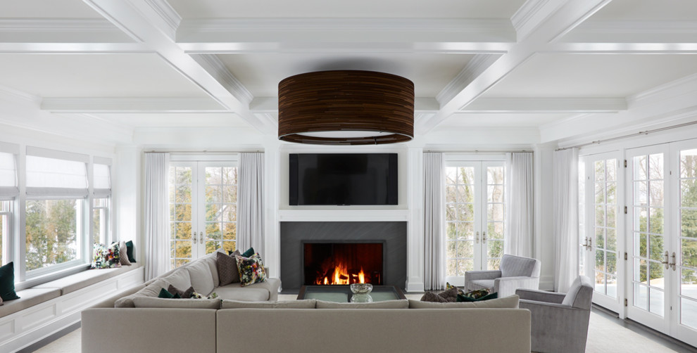 Photo of a transitional family room in New York with white walls and a wall-mounted tv.