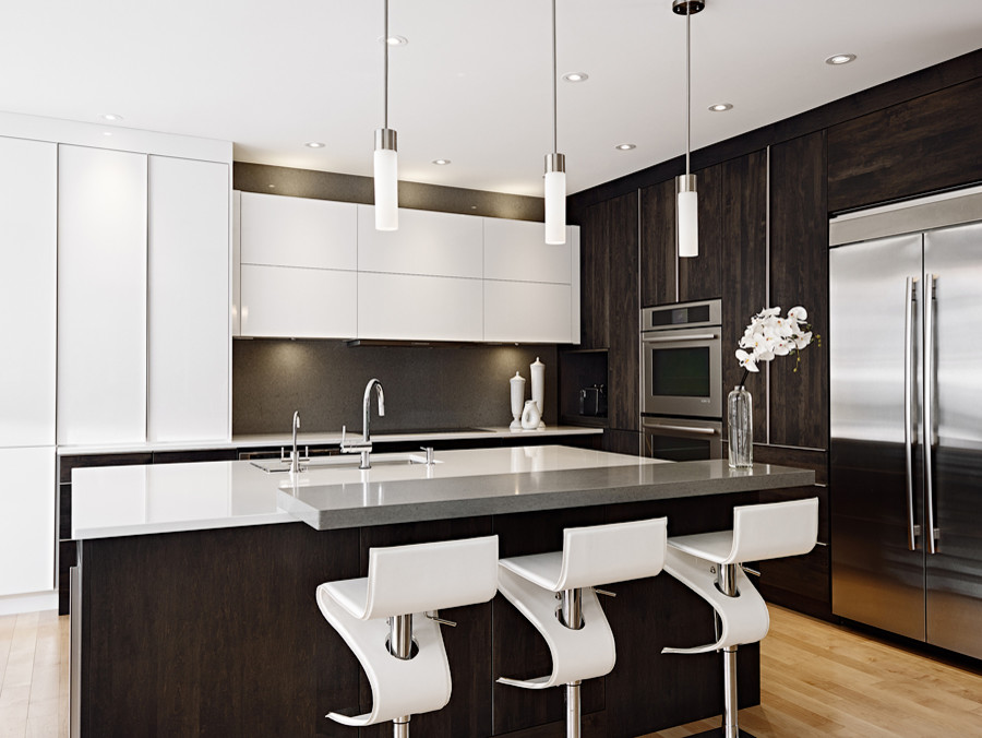 Example of a large minimalist l-shaped light wood floor eat-in kitchen design with an undermount sink, flat-panel cabinets, white cabinets, quartz countertops, stone slab backsplash, stainless steel appliances and an island