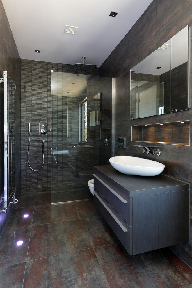 Contemporary bathroom in London with a vessel sink, flat-panel cabinets, dark wood cabinets, wood benchtops, a corner shower, grey walls and grey benchtops.