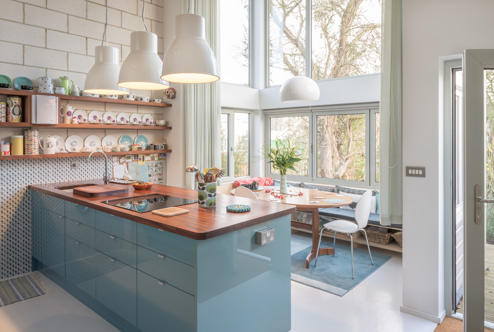 Mid-sized scandinavian eat-in kitchen in Oxfordshire with an undermount sink, flat-panel cabinets, blue cabinets, wood benchtops, with island and grey floor.