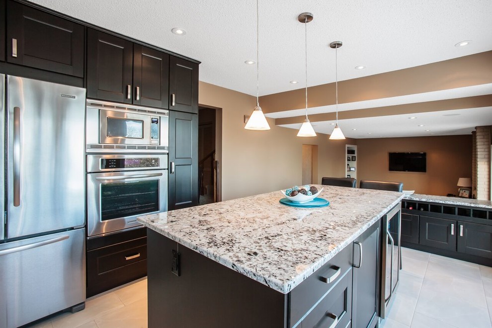 Example of a mid-sized transitional u-shaped ceramic tile and beige floor enclosed kitchen design in Calgary with a double-bowl sink, shaker cabinets, dark wood cabinets, granite countertops, beige backsplash, matchstick tile backsplash, stainless steel appliances and an island