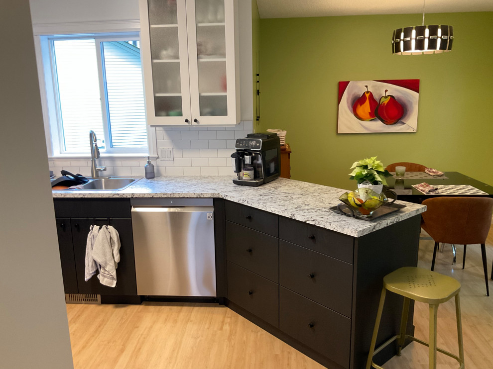 Contemporary black and white kitchen with white cabinets, black island, and pend
