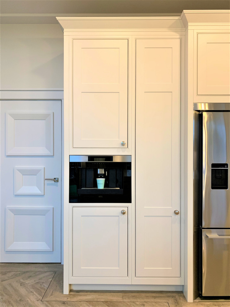Immagine di una grande cucina chic con lavello a doppia vasca, ante in stile shaker, ante in legno chiaro, top in quarzite, paraspruzzi bianco, elettrodomestici neri, pavimento in vinile e top bianco