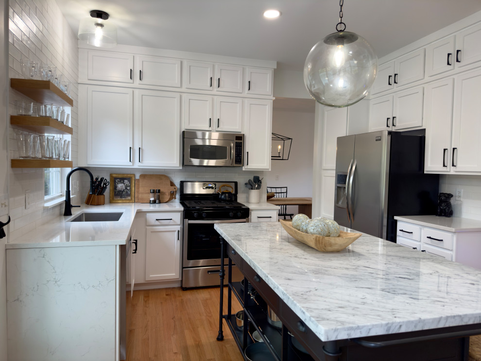 This is an example of a small contemporary u-shaped open plan kitchen in Chicago with an undermount sink, shaker cabinets, white cabinets, quartz benchtops, white splashback, subway tile splashback, stainless steel appliances, light hardwood floors, with island, orange floor and white benchtop.