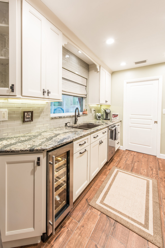 Example of a mid-sized transitional galley porcelain tile and brown floor eat-in kitchen design with an undermount sink, white cabinets, quartz countertops, gray backsplash, glass tile backsplash, stainless steel appliances, no island and shaker cabinets