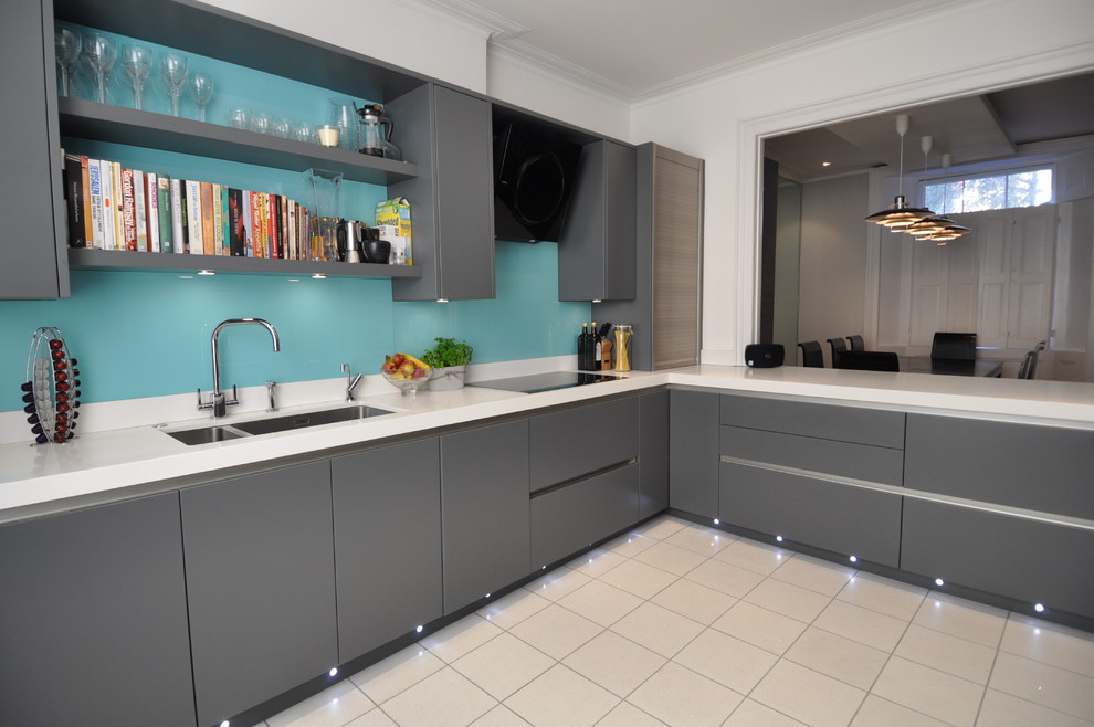 Inspiration for a mid-sized contemporary u-shaped separate kitchen in London with an undermount sink, flat-panel cabinets, grey cabinets, quartzite benchtops, blue splashback, glass sheet splashback, stainless steel appliances and porcelain floors.