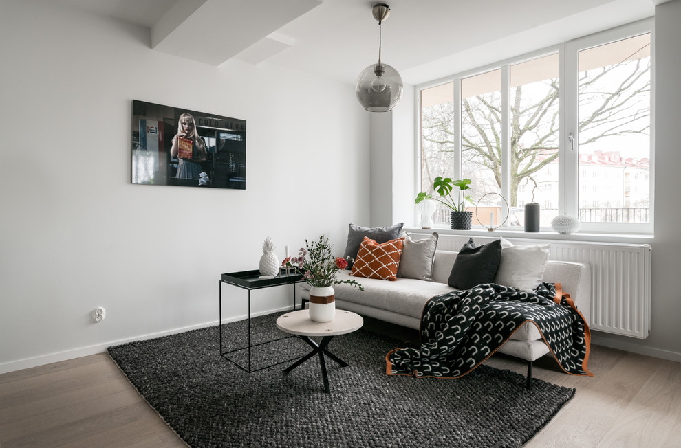 Skandinavisk inredning av ett litet separat vardagsrum, med vita väggar, laminatgolv, beiget golv och en väggmonterad TV