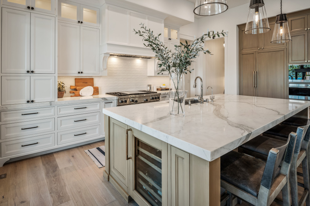 Inspiration for an expansive transitional open plan kitchen in San Francisco with an undermount sink, beaded inset cabinets, white cabinets, marble benchtops, white splashback, ceramic splashback, panelled appliances, light hardwood floors, with island, beige floor, white benchtop and exposed beam.