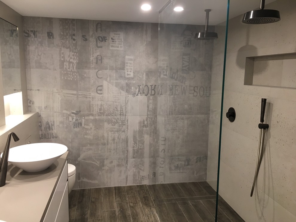 Photo of a large industrial master bathroom in Sydney with flat-panel cabinets, white cabinets, an open shower, a one-piece toilet, beige tile, stone slab, beige walls, porcelain floors, a vessel sink, an open shower, engineered quartz benchtops, brown floor, beige benchtops, a niche and a double vanity.