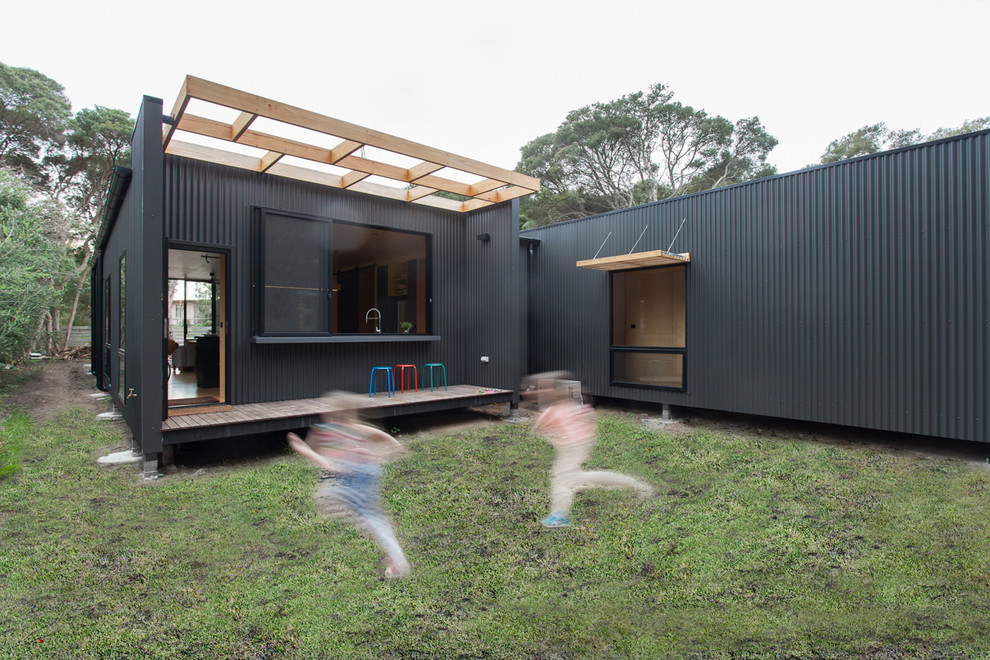 Inspiration for a mid-sized contemporary grey exterior in Melbourne with metal siding and a flat roof.