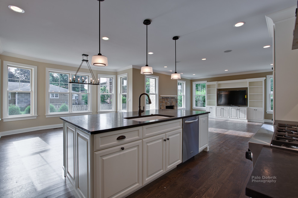 This is an example of a traditional kitchen in Chicago with a single-bowl sink, raised-panel cabinets, white cabinets, stainless steel appliances, medium hardwood floors and with island.