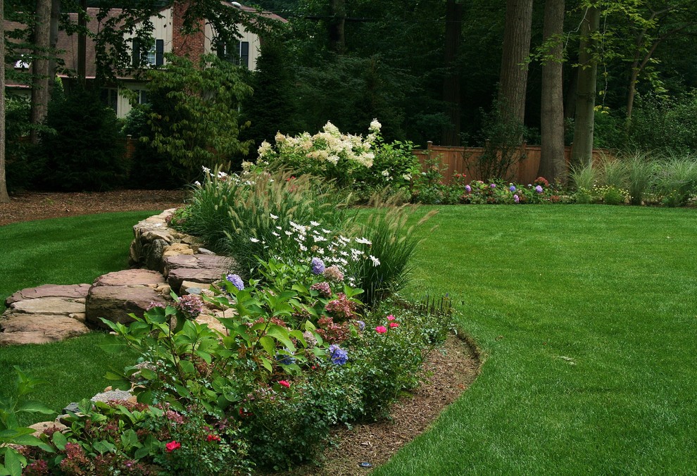 Photo of a large traditional backyard partial sun garden for summer in New York with a retaining wall and brick pavers.