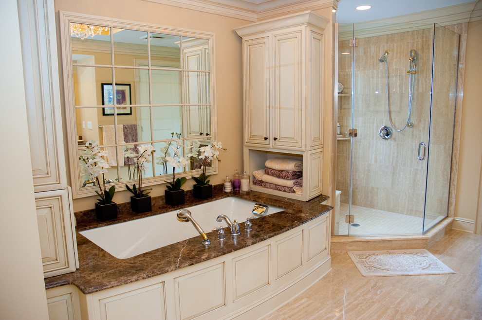 Inspiration for a traditional bathroom in New York with an undermount sink, raised-panel cabinets, light wood cabinets, granite benchtops, an undermount tub, a corner shower, a two-piece toilet and beige tile.