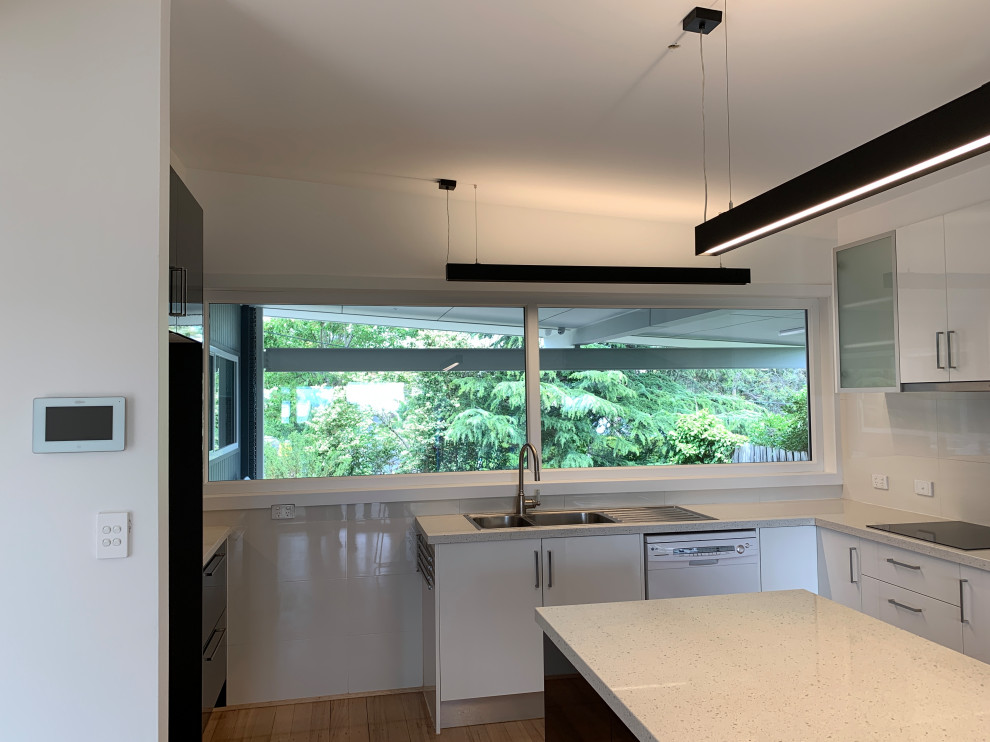 Midcentury kitchen in Melbourne with a double-bowl sink, black appliances and with island.