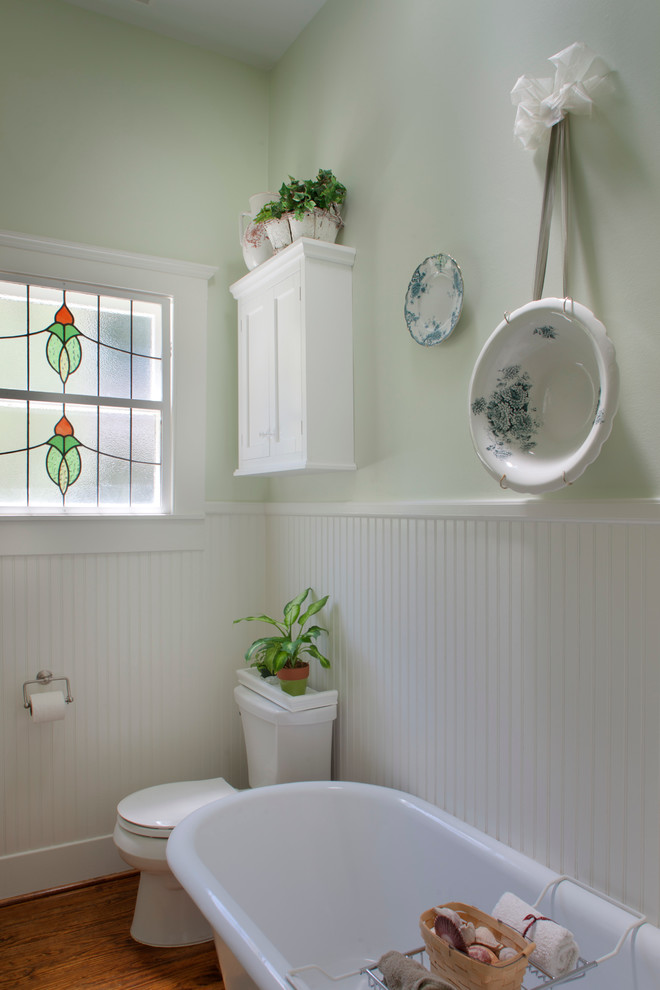 Photo of a mid-sized traditional kids bathroom in Houston with flat-panel cabinets, white cabinets, granite benchtops, a freestanding tub, a two-piece toilet, green walls, medium hardwood floors and a pedestal sink.