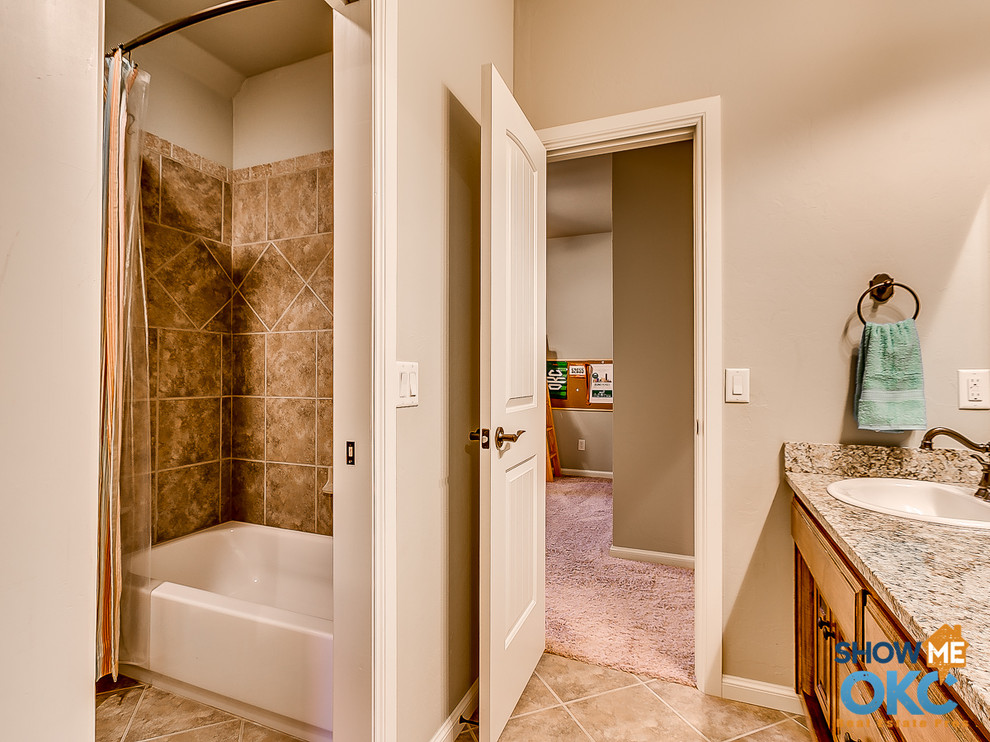 This is an example of a traditional kids bathroom in Oklahoma City with a drop-in sink, granite benchtops, a shower/bathtub combo and ceramic floors.