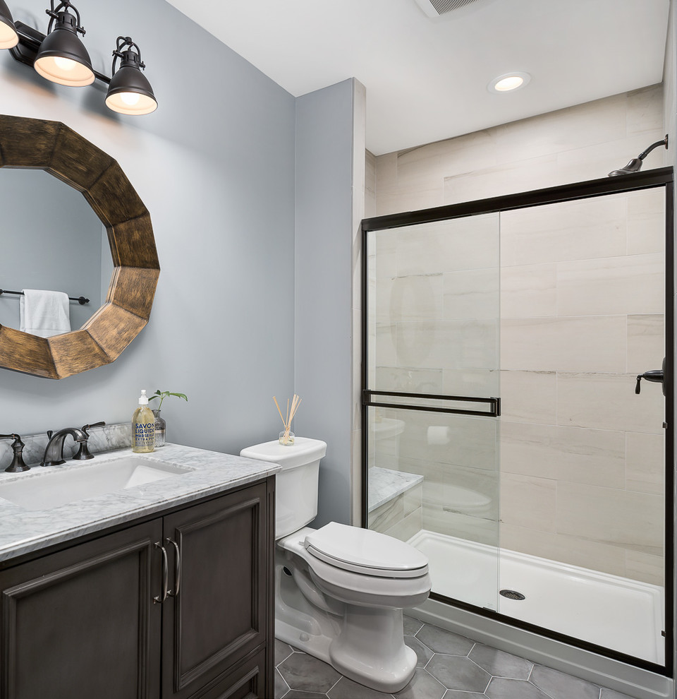 Photo of a mid-sized transitional 3/4 bathroom in Chicago with brown cabinets, an alcove shower, a two-piece toilet, ceramic floors, an undermount sink, marble benchtops, grey floor, a sliding shower screen, beige tile, blue walls and recessed-panel cabinets.