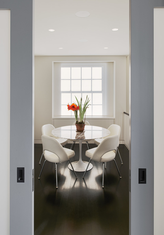 Photo of a transitional dining room in New York with white walls and dark hardwood floors.