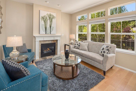Photo of a small transitional formal open concept living room in Seattle with beige walls, light hardwood floors, a standard fireplace, a tile fireplace surround and no tv.