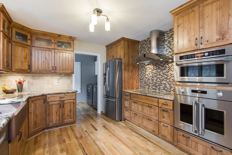 Eat-in kitchen - large rustic light wood floor eat-in kitchen idea with a farmhouse sink, light wood cabinets, granite countertops, beige backsplash, glass tile backsplash, stainless steel appliances and beige countertops