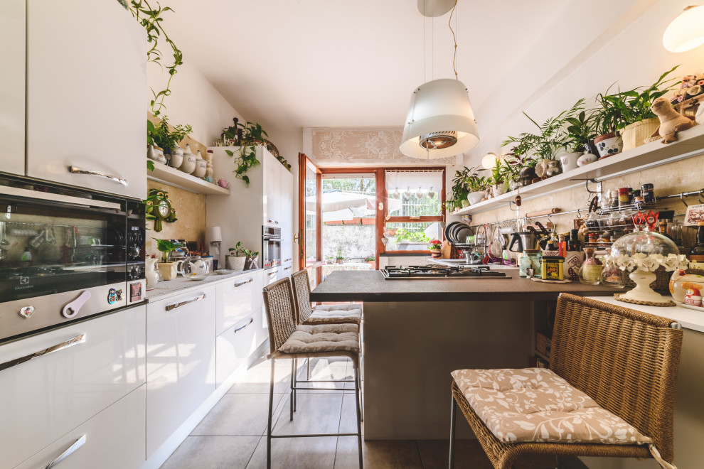 This is an example of a small eclectic galley kitchen in Other with white cabinets, marble benchtops, marble splashback, stainless steel appliances, ceramic floors, a peninsula, grey floor, grey benchtop, flat-panel cabinets and beige splashback.